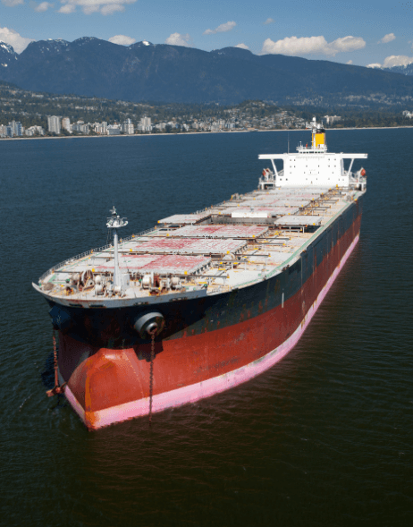 Cargo ship sailing near coastal mountains.