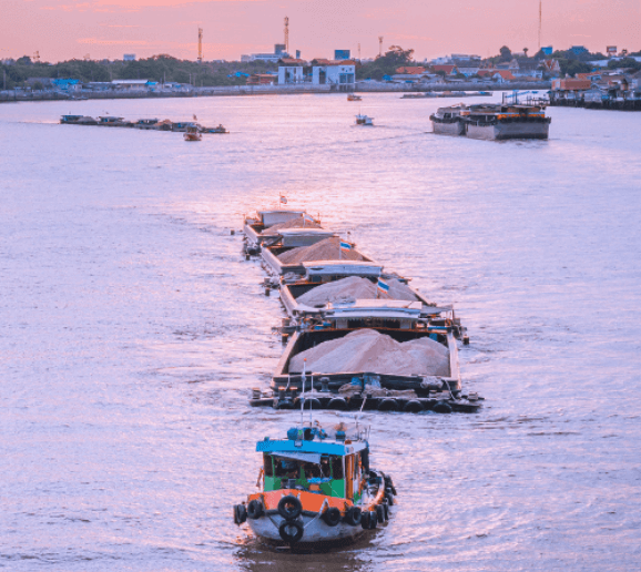 Boat towing barges on a calm river.
